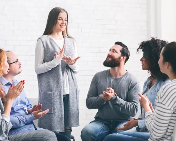 A woman talking to a group therapy session