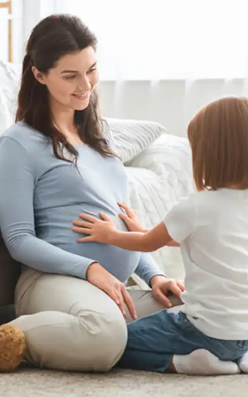 A pregnant woman with a child pressing her hands to her stomach